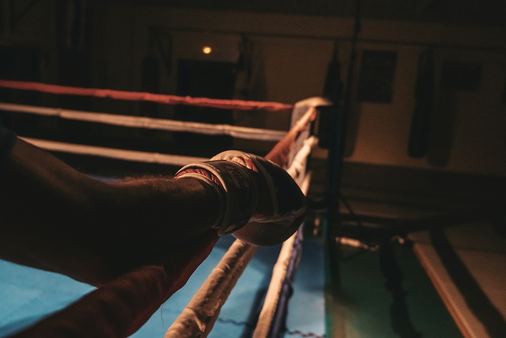 A closeup of a boxer's glove on the side of the ring.