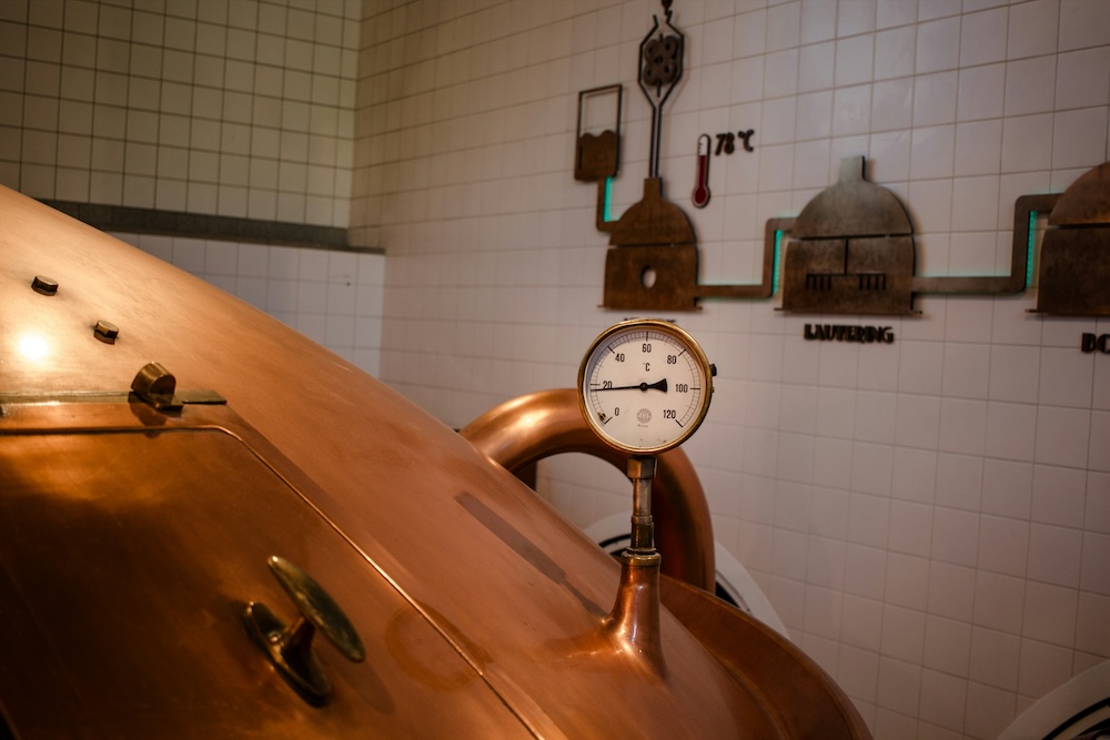 A close up of a copper vat with a temperature gauge.