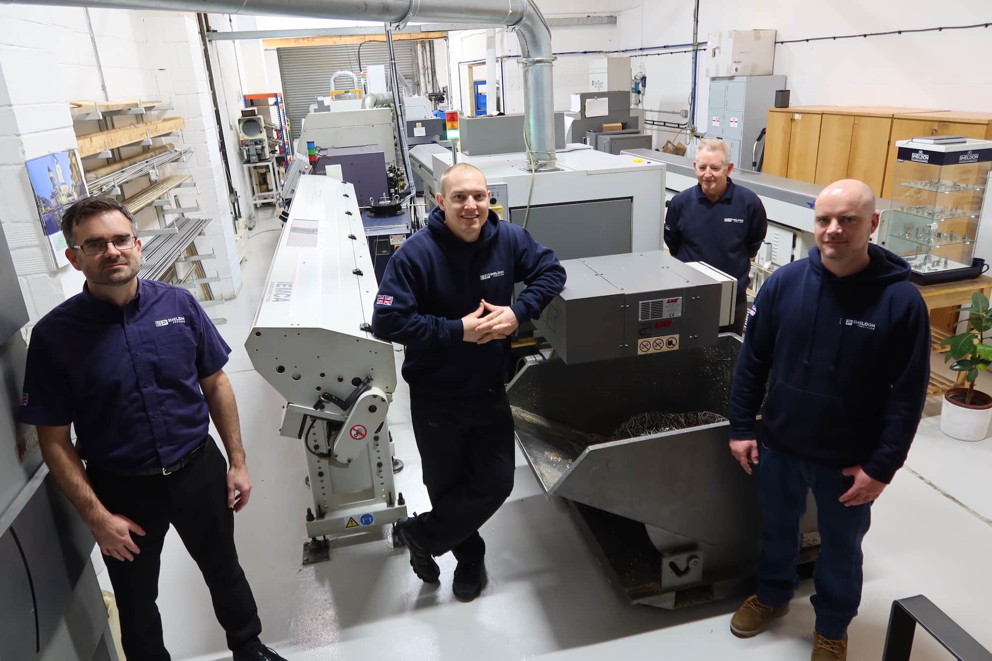 Sheldon Precision CNC machining team standing beside sliding head lathe in the precision engineering workshop